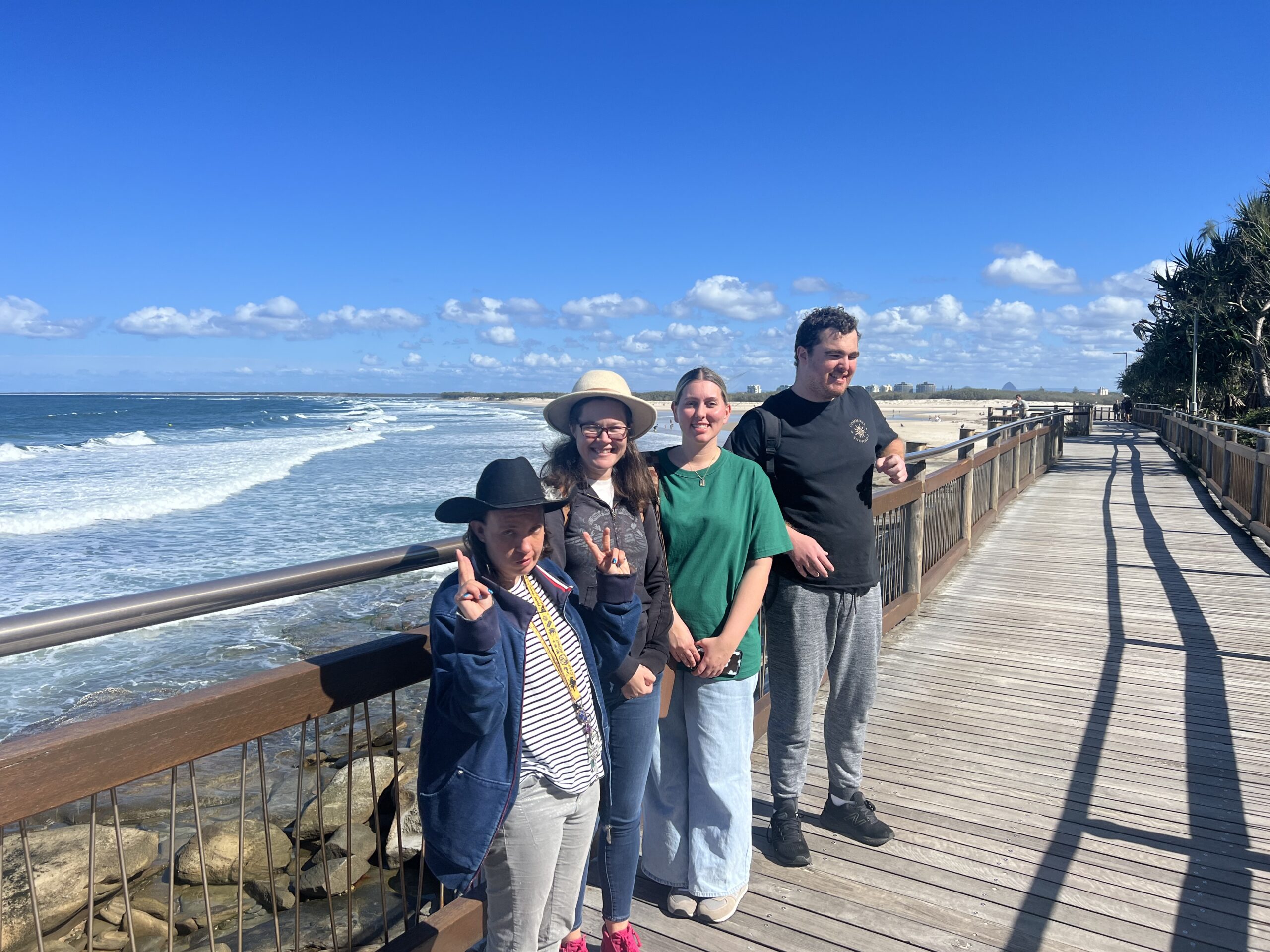 participants stand on a boardwalk in front of water smiling